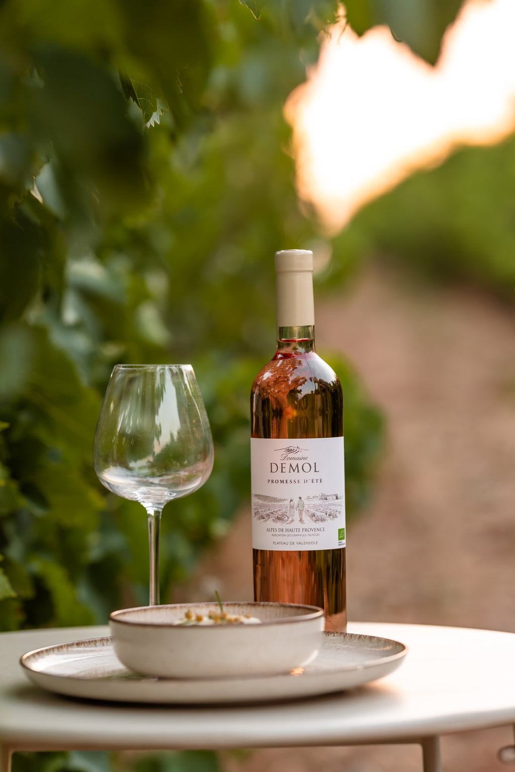 Bouteille de vin rosé BIO Promesse d'Été du Domaine Demol au milieu des vignes du domaine