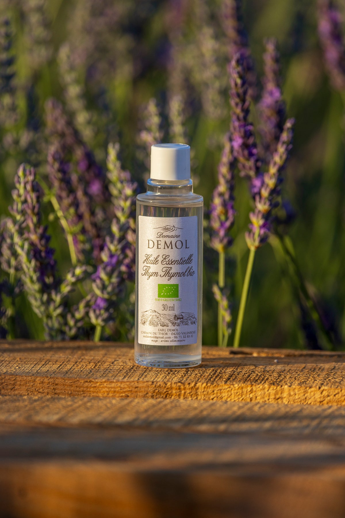 Flacon de 30 ml d'huile essentielle de thym à thymol BIO du Domaine Demol, devant un champ de lavande