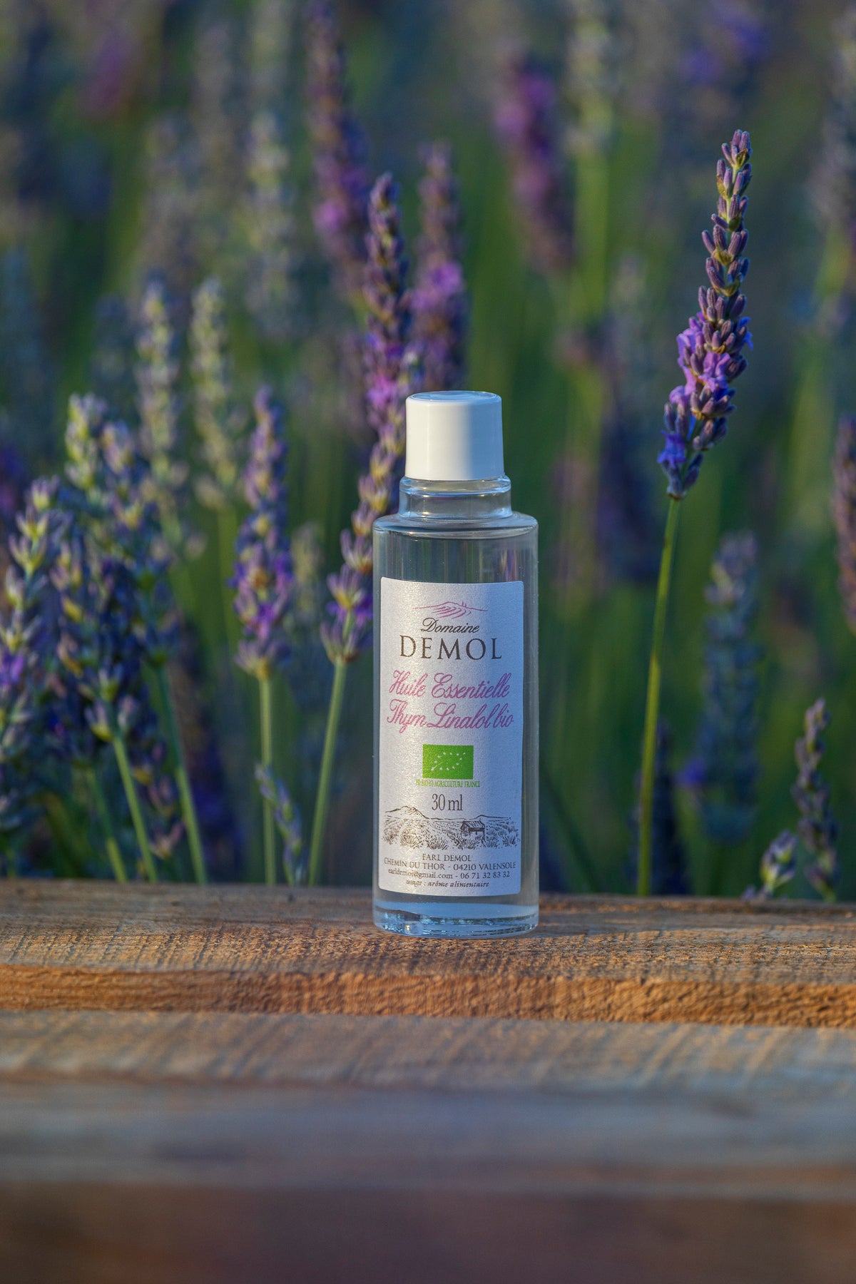 Flacon de 30 ml d'huile essentielle de thym à linalol BIO du Domaine Demol, posé sur une poutre en bois