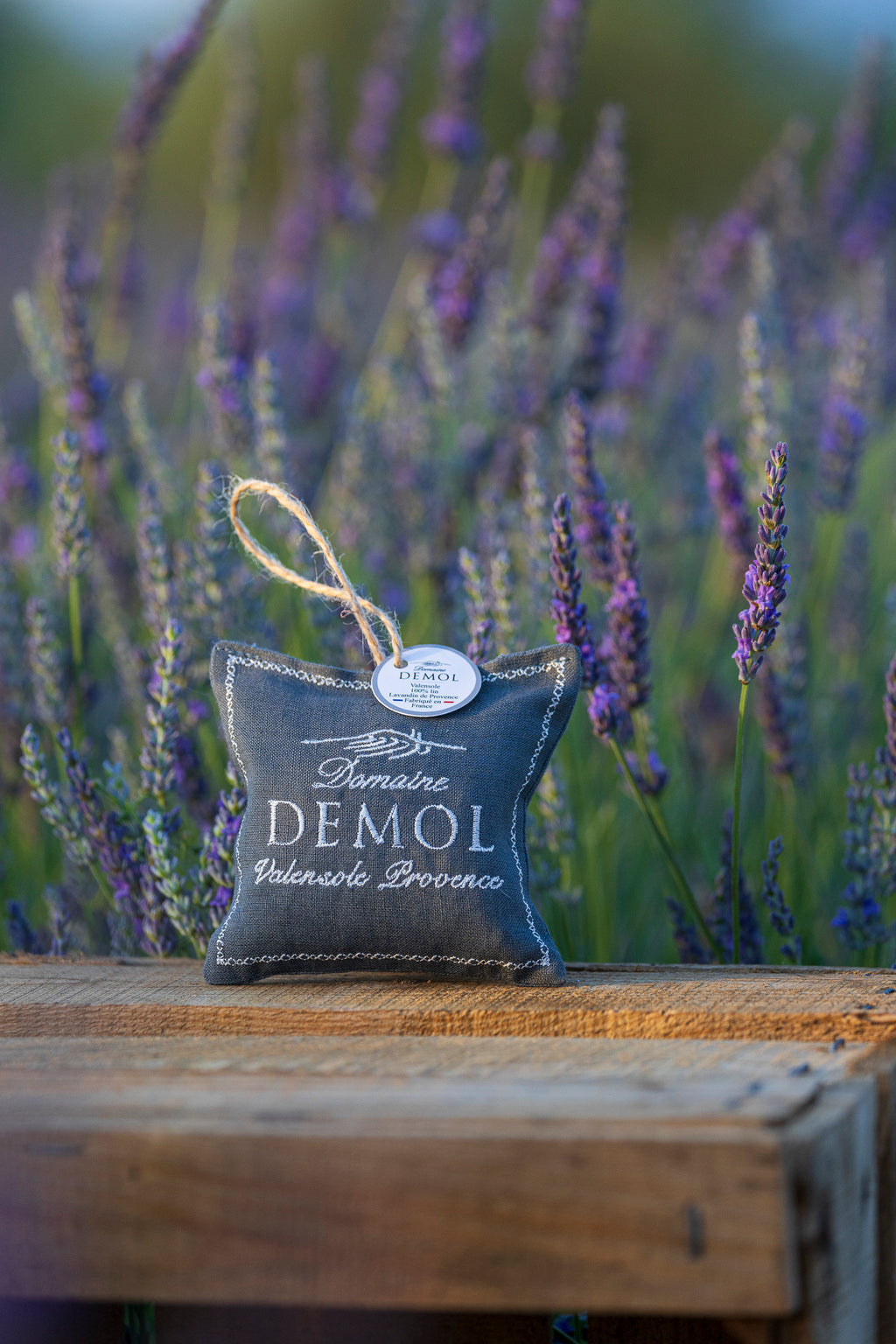 Coussinet de lavande Domaine Demol Valensole Provence posé sur une poutre, lavandes en arrière-plan