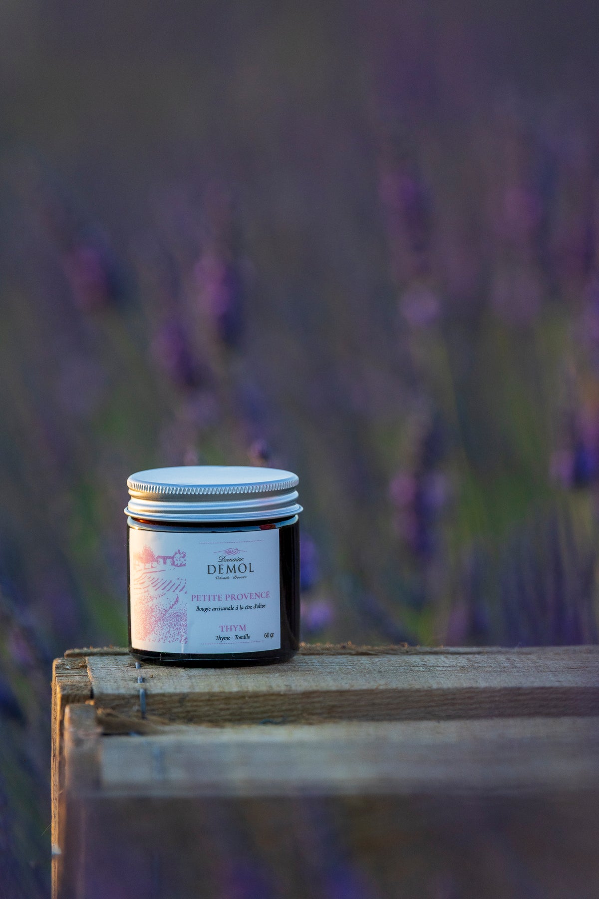 Bougie artisanale à la cire d'abeille Petite Provence parfum thym, devant un champ de lavande