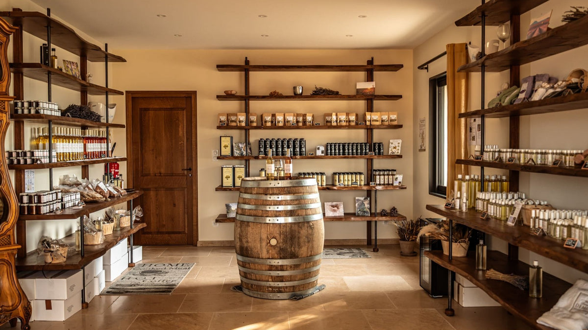 Intérieur de la boutique du domaine Demol, étagères en bois avec les produits By Louys et un tonneau