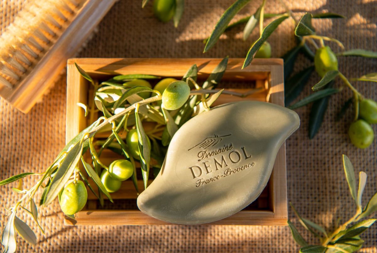 Savon à l'huile d'olive du Domaine Demol dans une cagette, entouré de rameaux d'olivier