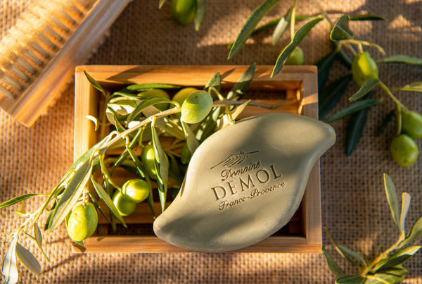 Savon à l'huile d'olive du Domaine Demol dans une cagette, entouré de rameaux d'olivier